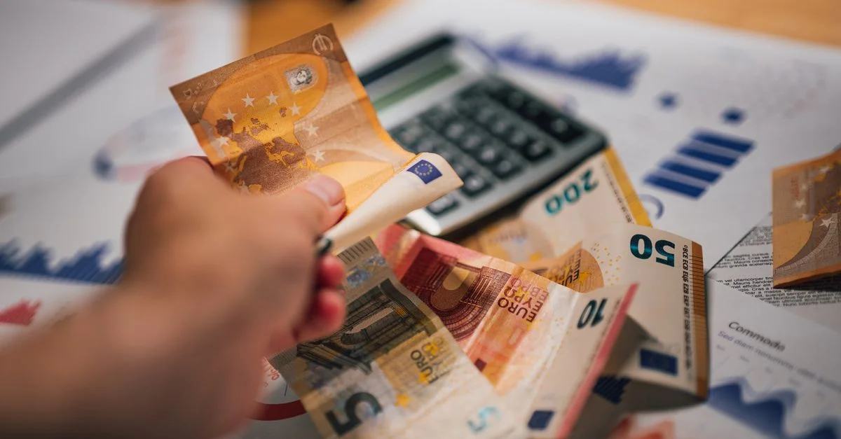 Gros plan sur des billets Euro sur des documents financiers et une calculatrice, illustrant la planification financière.
