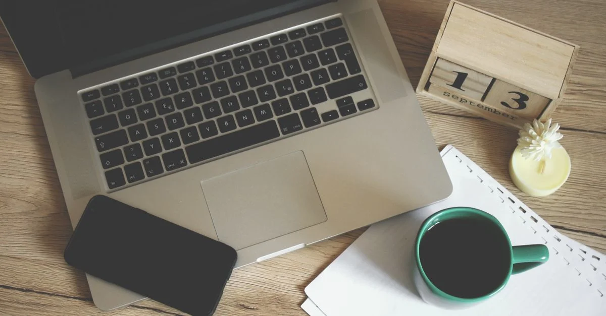 Bureau moderne avec ordinateur portable, smartphone, café et calendrier pour un environnement de travail productif.