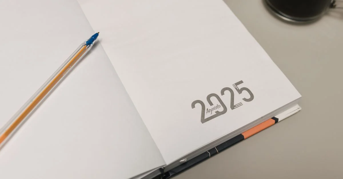 Agenda 2025 ouvert avec un stylo et une tasse de café sur un bureau, idéal pour des thèmes de productivité.
