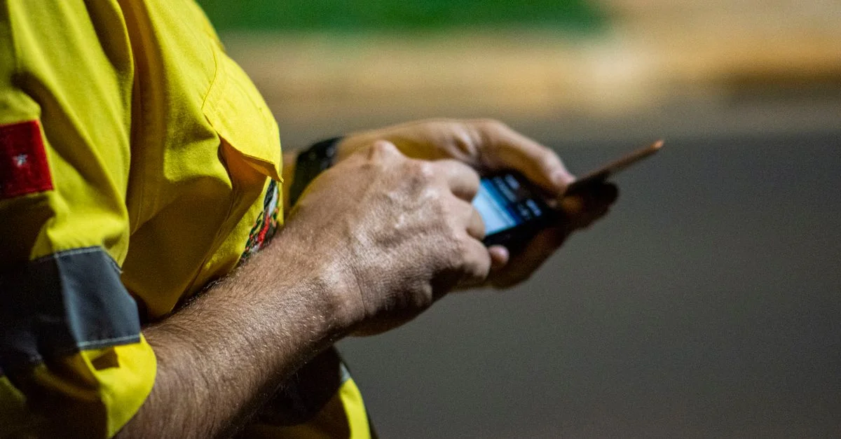 Primer plano de manos usando un smartphone al aire libre por la noche en Londrina, Brasil.