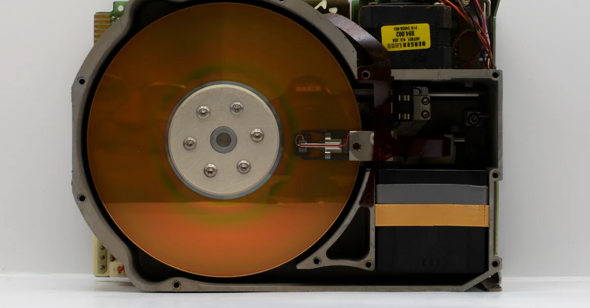 Primer plano de un disco duro antiguo abierto que muestra sus componentes internos.