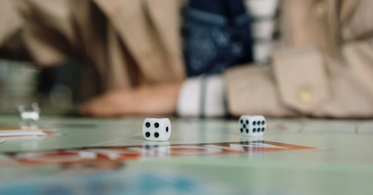 Toma enfocada de dados en acción durante un juego de mesa con un jugador en el fondo.