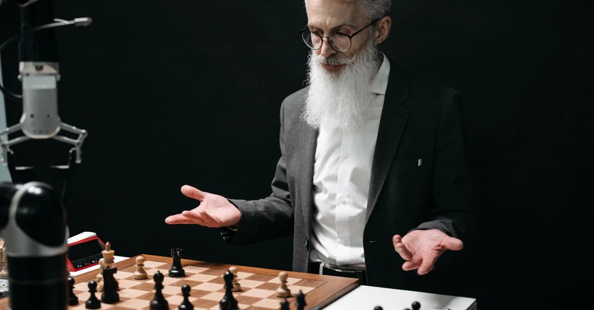 Un homme âgé joue aux échecs contre un robot, alliant tradition et technologie moderne.