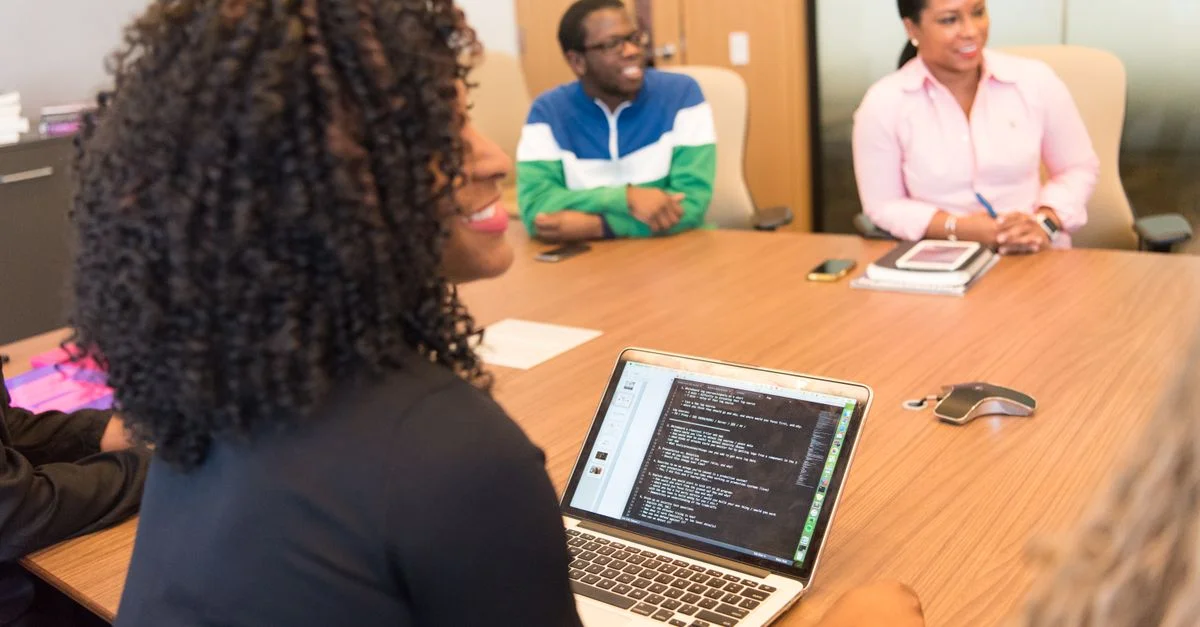 Un grupo diverso de profesionales colaborando en un entorno de oficina moderno con laptops y tecnología.
