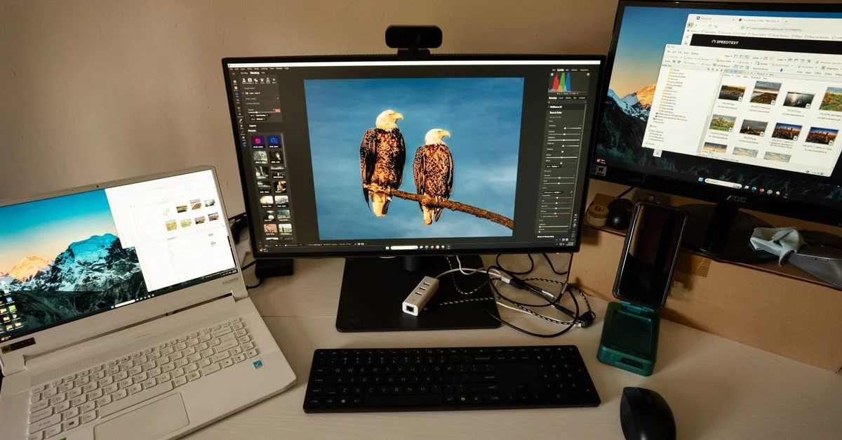 Espacio de trabajo del fotógrafo con monitores duales, laptop y software de edición.