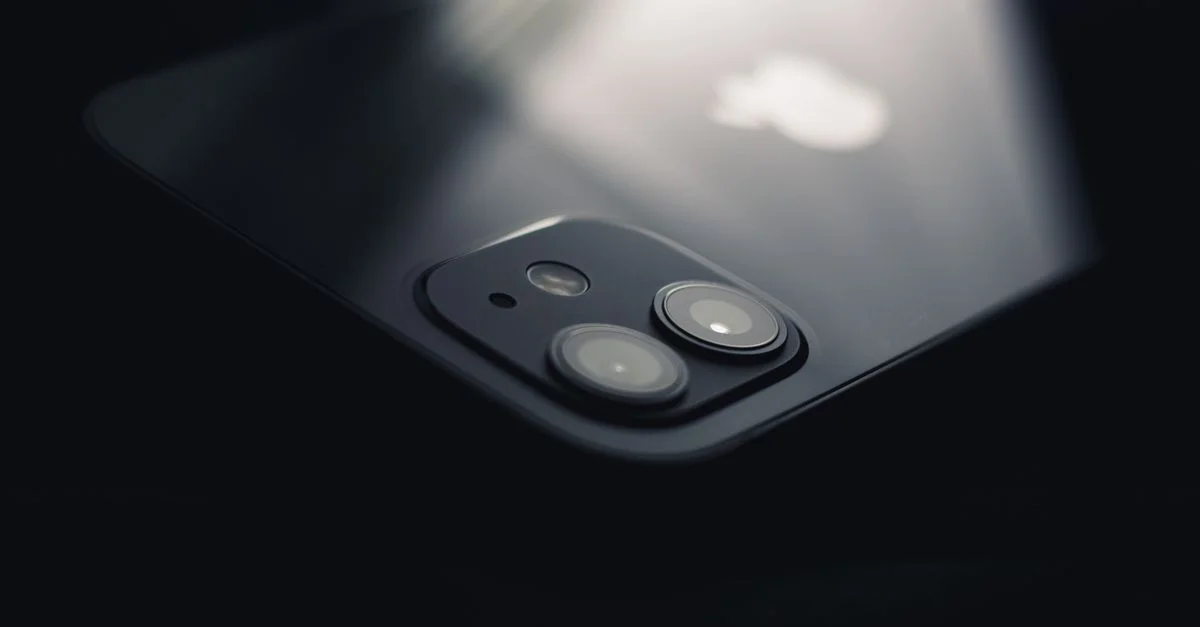 Toma en primer plano de una lente de cámara de smartphone reflejando luz, destacando la tecnología moderna.
