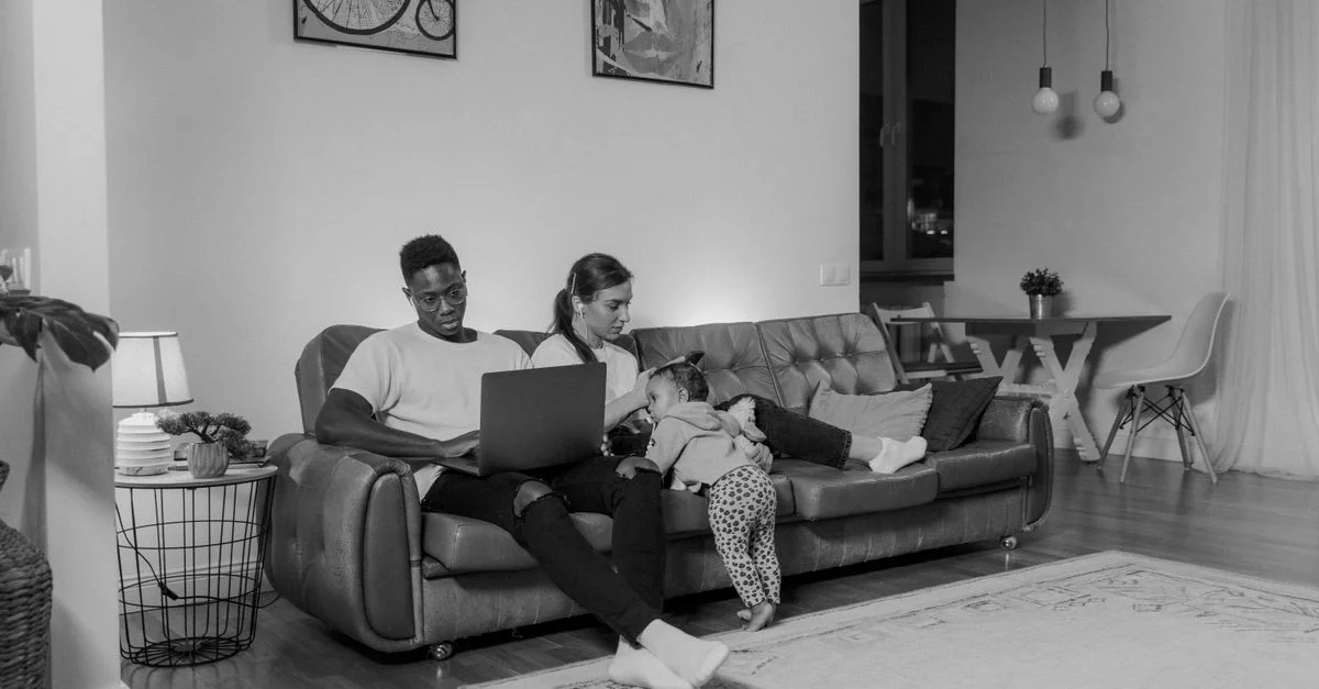 Una familia disfrutando de tiempo de calidad juntos en un sofá, usando un portátil en una cómoda sala de estar.