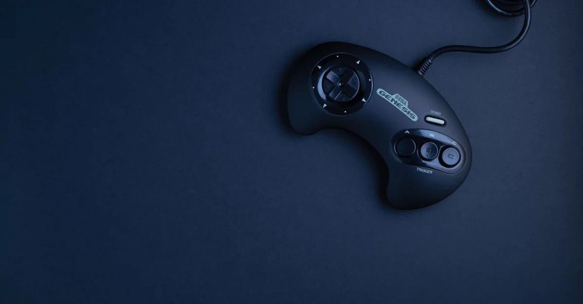 Controlador de consola de juego vintage azul marino fotografiado desde arriba sobre un fondo oscuro.