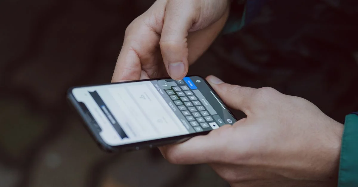 Primer plano de una persona enviando mensajes en un smartphone. Entorno al aire libre con conectividad inalámbrica.