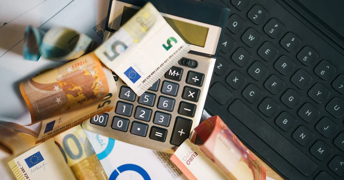 Un entorno financiero que presenta billetes de euro, una calculadora y un teclado de portátil para el análisis empresarial.
