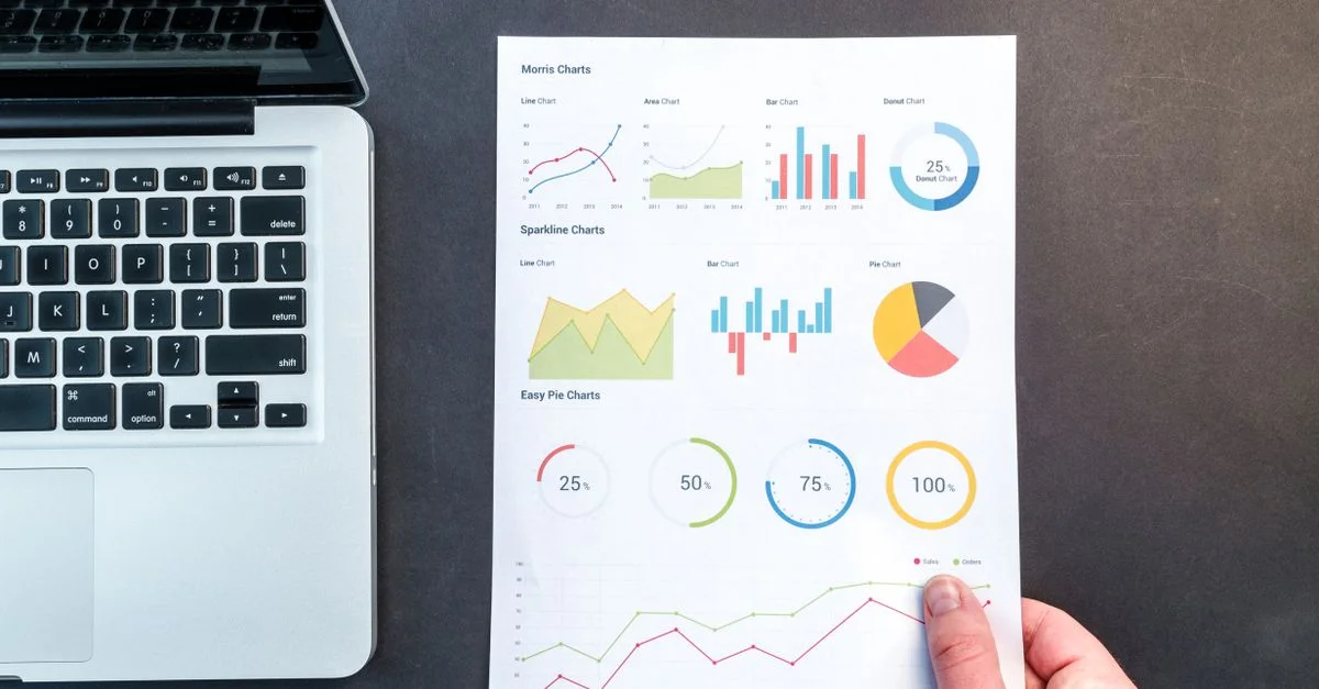 Gráficos y tablas detallados en un documento junto a un portátil, representando análisis de datos.