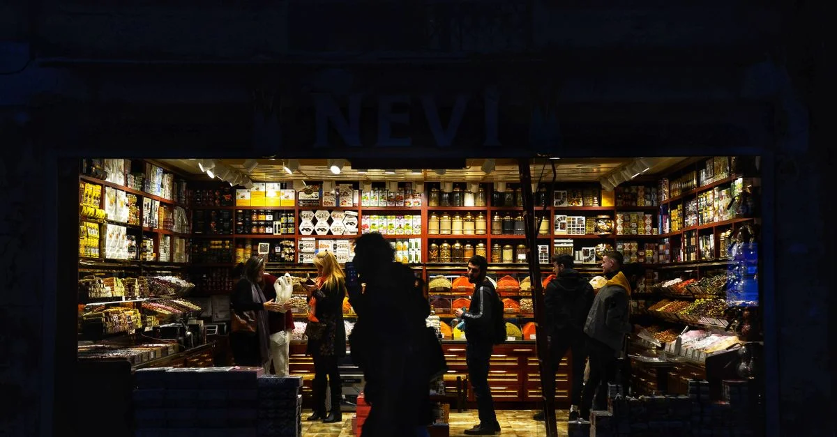 Una vibrante tienda iluminada en la calle llena de personas comprando por la noche.