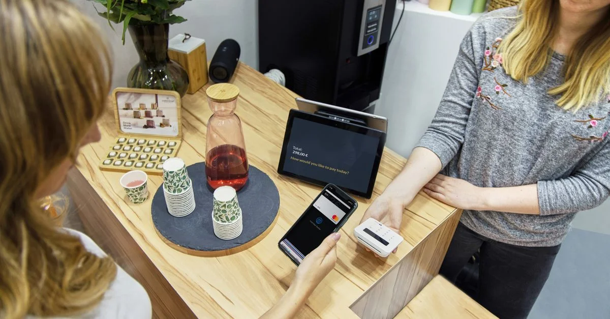 Una mujer realiza un pago sin contacto en un elegante café de Berlín, enfatizando la tecnología y el comercio moderno.