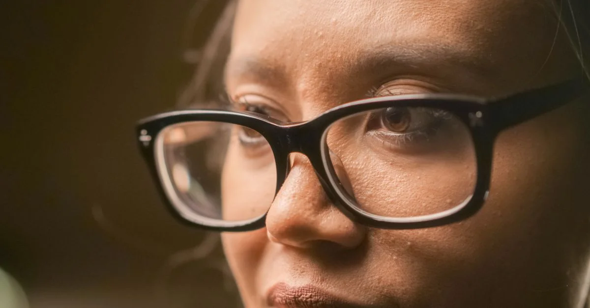Primer plano detallado de una persona con gafas, mostrando concentración y contemplación.