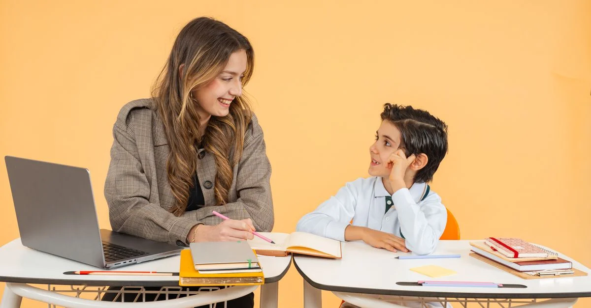 Un profesor y un estudiante sonríen mientras participan en una actividad de aprendizaje en un aula.