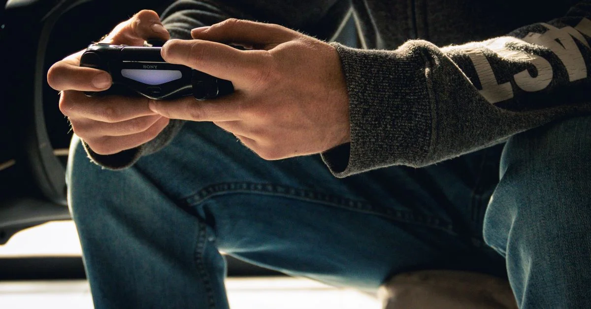Imagen en primer plano de unas manos sosteniendo un mando de videojuegos, lo que enfatiza una sesión de juego en interiores.