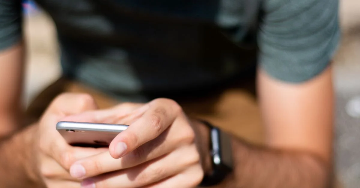Primer plano de manos usando un smartphone al aire libre, que muestra la comunicación móvil moderna.
