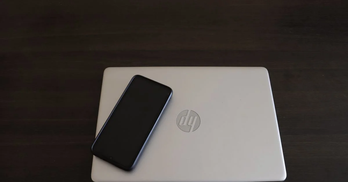 Primer plano de un smartphone apoyado en un portátil HP, simbolizando la integración de la tecnología moderna.