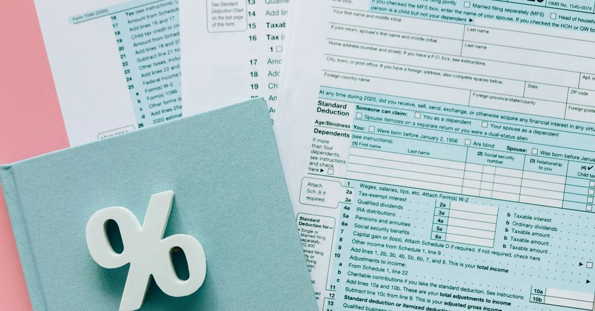 Documents fiscaux avec un symbole de pourcentage sur un bureau rose et bleu, mettant l'accent sur la finance.