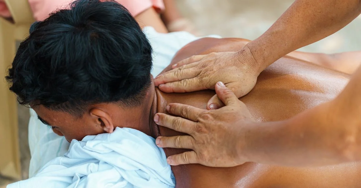 Gros plan d'une séance de massage relaxant en extérieur avec un focus sur les mains et le dos.
