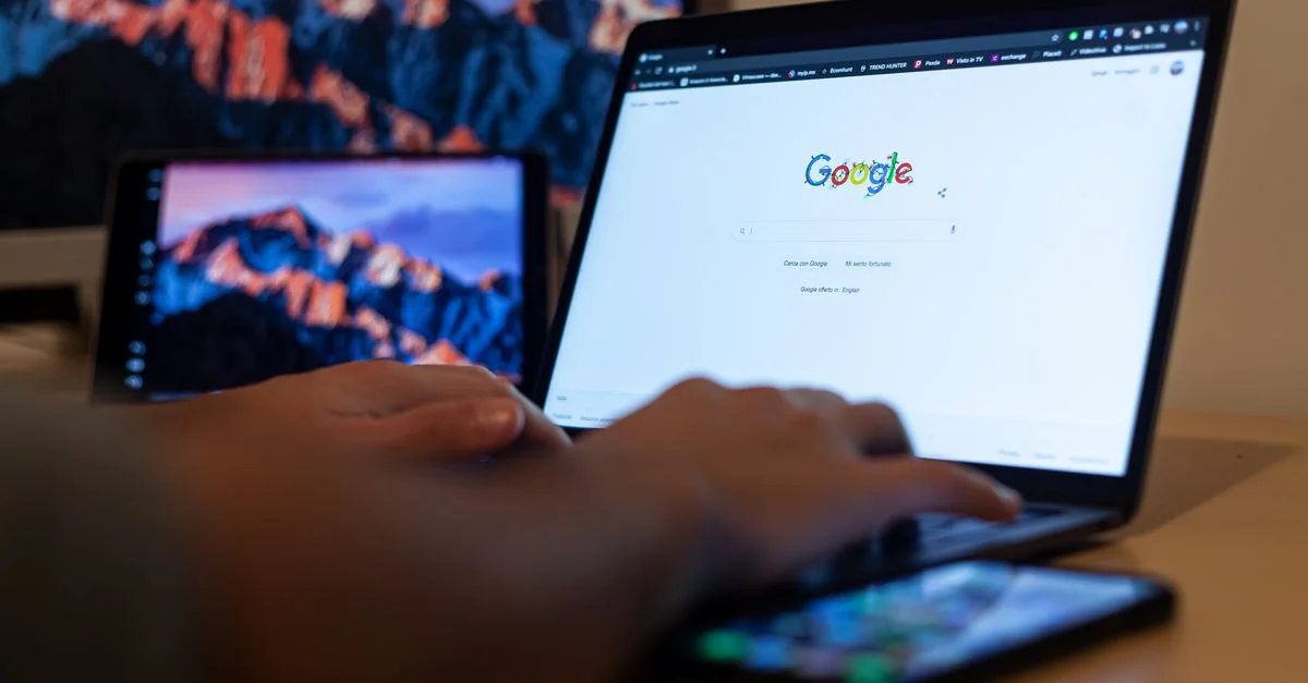 Manos tecleando en un portátil con Google en pantalla, en un entorno de trabajo remoto en Milán, Italia.