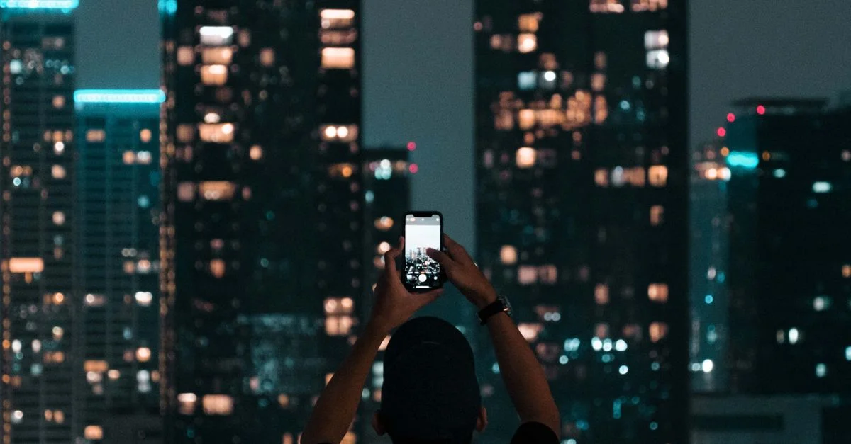 Una persona fotografiando los rascacielos iluminados de Yakarta durante una vibrante noche en la ciudad.
