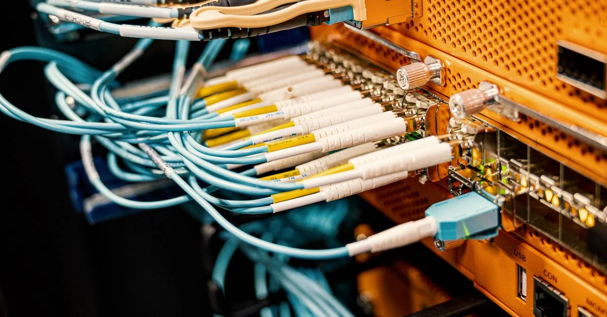 Primer plano de cables de red conectados a equipos en un centro de datos, mostrando una configuración de tecnología moderna.