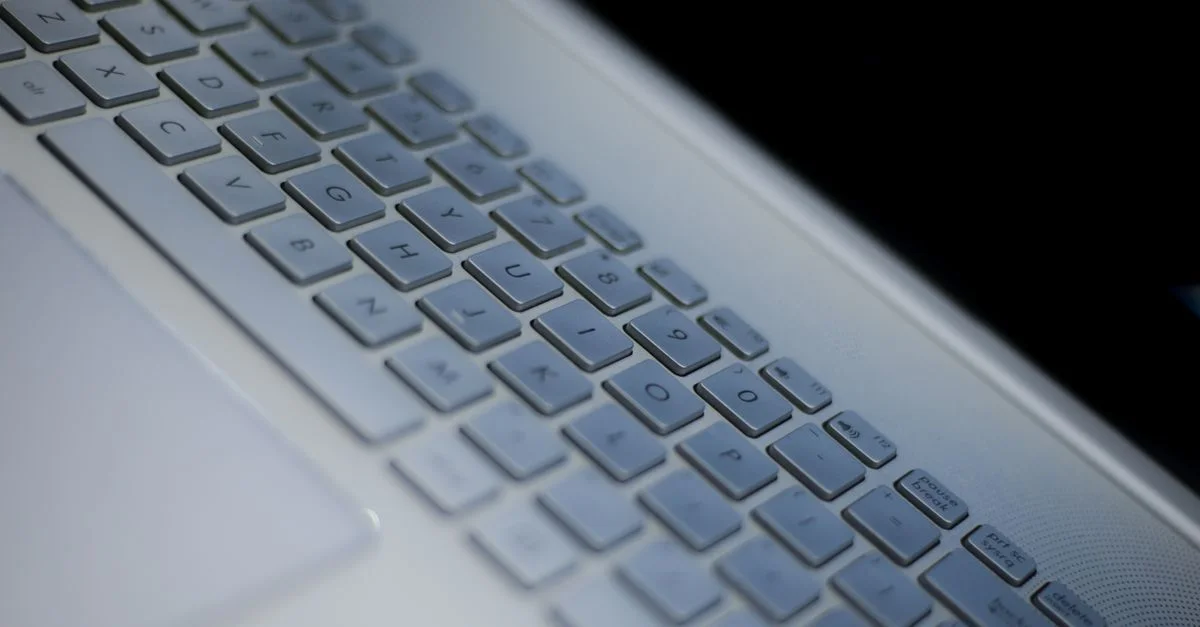 Vista detallada de un teclado de portátil blanco con iluminación ambiental.
