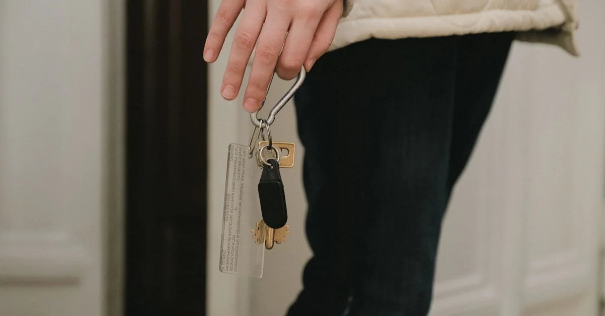 Una foto en primer plano de una mano adulta sosteniendo un juego de llaves de casa en el interior, sugiriendo seguridad y acceso al hogar.