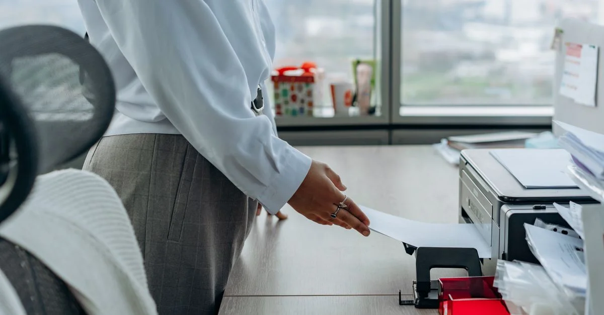 Profesional de negocios imprimiendo un documento en un entorno de oficina.